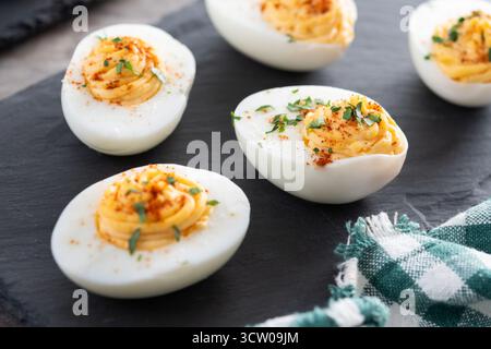 Homemade hard Boiled Deviled Eggs garnished with herbs on wooden table Stock Photo