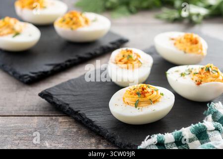 Homemade hard Boiled Deviled Eggs garnished with herbs on wooden table Stock Photo