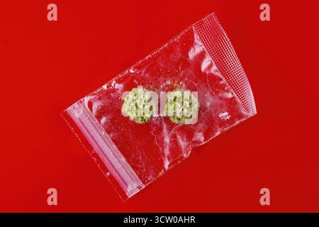 Plastic bag with Cannabis Buds isolated on red background. Stock Photo
