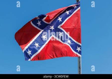Confederate flag flying against a blue sky Stock Photo