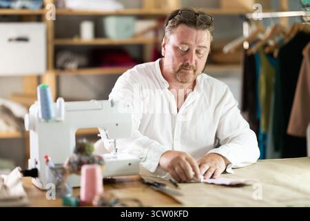 Middle-aged male dressmaker drawing detail on paper with chalk Stock Photo