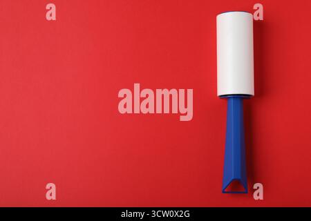 One lint roller on red background, top view. Space for text Stock Photo