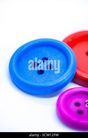 buttons on white surface, very soft focus with focus on the holes of the blue button Stock Photo