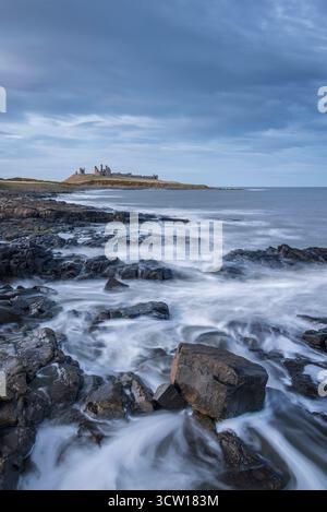 Dunstanburgh Castle from the rocky ledges near Craster in Northumberland, England.  Winter (March) 2025. Stock Photo