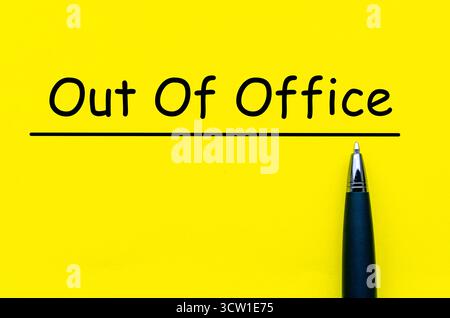 Out Of Office, Yellow square paper with black pen below the underlined phrase symbolizing absence notification note Stock Photo