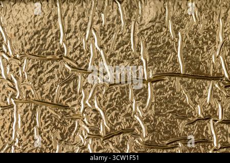 the golden crumpled surface used for packaging goods and food, the details of the golden foil for packaging and long-term storage of food Stock Photo