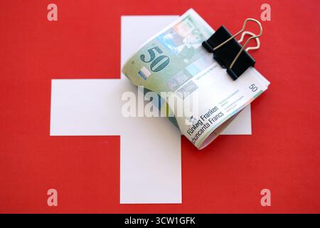 Swiss franc banknotes and flag. The current francs money bills lies on flag in big amount. The concept of business in Switzerland Stock Photo