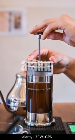 Barista using french press coffee maker, plunging freshly brewed coffee Stock Photo