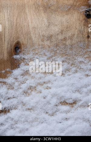 Close-up of snow lying on a wooden surface, showing a contrast between soft white snow and natural wood texture. Stock Photo