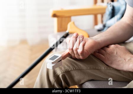 Caucasian middle aged man using pulse oximeter at home Stock Photo