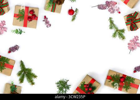 Christmas decoration. Frame of gift boxes, Christmas tree branch, red berries, pine cones on a white background. Top view Stock Photo
