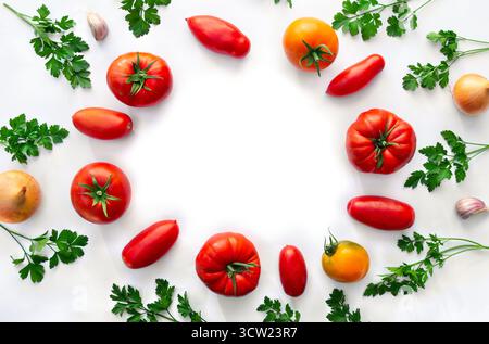 Red and yellow tomatoes, fresh tomatoes of various colors and cultivar, parsley, onion, garlic on a white background with space for text. Top view Stock Photo