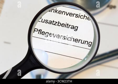 (Photo montage) Close-up of the word PFLEGEVERSICHERUNG (long-term care insurance) on a document, enlarged with a magnifying glass Stock Photo