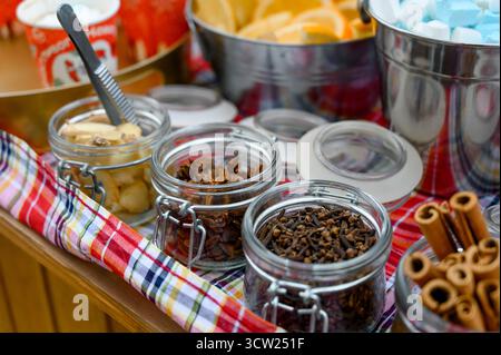 Jars with spices and additives for hot drinks: cloves, star anise, cinnamon and ginger. A set of spices in glass jars for preparing mulled wine or tea Stock Photo