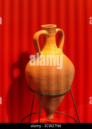 Terracotta Amphora on Metal Stand with Red Background Stock Photo