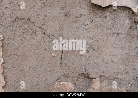 Weathered, cracked concrete wall with rough, gritty texture and peeling paint, showing signs of decay and neglect Stock Photo