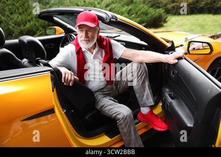 Stylish senior man getting out of modern cabriolet outdoors Stock Photo