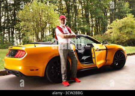 Stylish senior man getting out of modern cabriolet outdoors Stock Photo