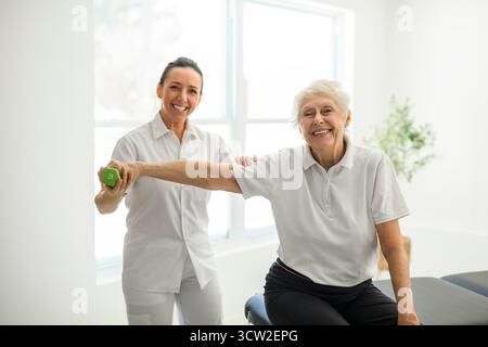 A physiotherapist helping senior woman in clinic. Elderly woman undergoing physiotherapy treatment for injury Stock Photo