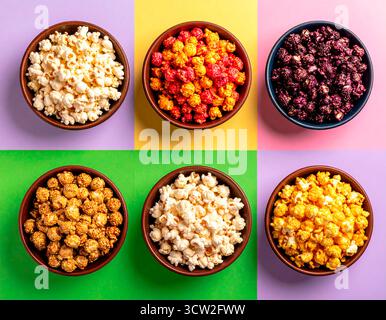 Bowls displaying various flavored popcorn on a multicolored background, creating a vibrant snack selection from above Stock Photo