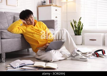 Student with laptop and books preparing for exam on floor at home Stock Photo