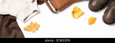 Autumn cloth and accessories at white background. Scarf, sweater ad bag with fallen leaves. Long banner format. Stock Photo