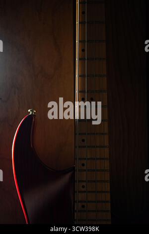 Bass Guitar hanging on the wall as the sun sets Stock Photo