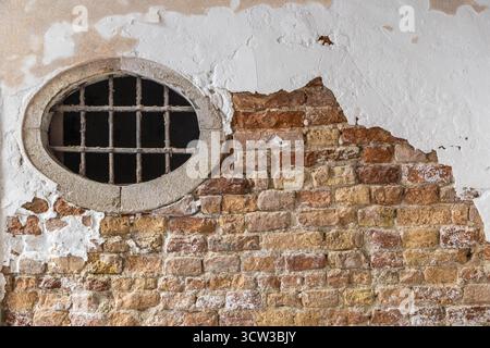 old brick wall with an oval window, peeling paint, architectural detail Stock Photo