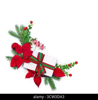 Top view Christmas composition with fir tree branches, red poinsettia flowers, red berries, gift box with ribbon on white background. Holiday flat lay Stock Photo