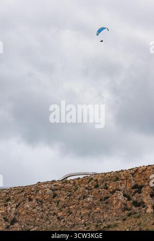 Unrecognizable paraglider with clouds and a vertical wall next to the Santa Pola lighthouse viewpoint, Spain Stock Photo