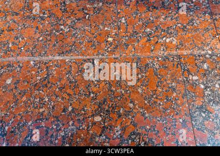 Polished granite floor with red and black stone pattern. Smooth natural texture used in architecture, interior design, and decoration. Stock Photo
