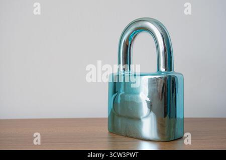 A sharp, stylized shot captures a bright metal padlock securely resting on a smooth brown surface, which is isolated against a clean white background. Stock Photo