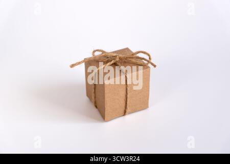 A clean, minimalist shot features a cubed box package seamlessly wrapped in natural brown kraft paper. It is secured with rustic, rough twine Stock Photo