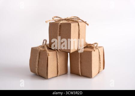 A clean, striking still life features three identical cube-shaped gift boxes, all neatly crafted from natural brown kraft paper Stock Photo
