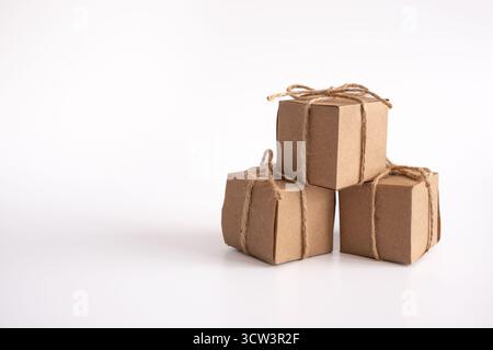 A clean, striking still life features three identical cube-shaped gift boxes, all neatly crafted from natural brown kraft paper Stock Photo