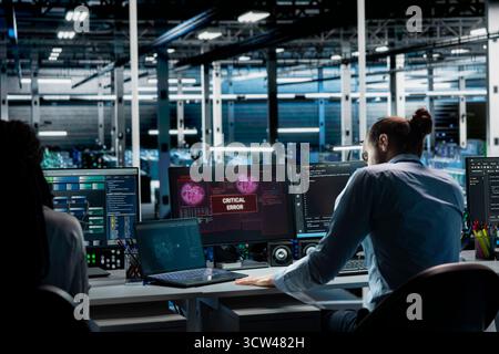 Teamworking data center admins try to fix malfunctions using AI tools. Server farm IT specialists doing brainstorming to optimize system health, repairing critical error with artificial intelligence Stock Photo