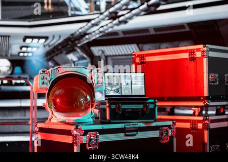 Red light over space helmet next to laptop in spaceship displaying mission analytics panel with flight metrics. Hazard alert during space journey, light blinking over astronaut gear Stock Photo