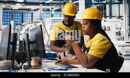 African american workers checking up on manufacturing equipment in solar panel factory, reading documentation files. Team of engineers in industrial facility inspecting production process. Camera B. Stock Photo