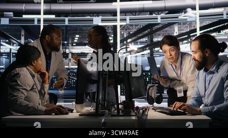 Programmers doing brainstorming in server room, reviewing neural network code and LLM visualization dashboards. Data center coworkers monitoring artificial intelligence systems performance, camera A Stock Photo