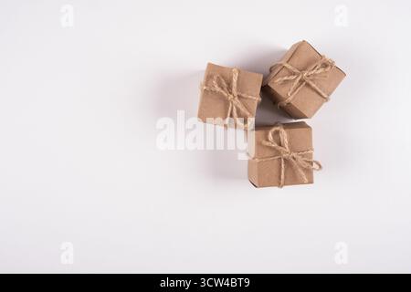 Brown gift boxes wrapped with kraft paper on white background. Top view of gift boxes tied with brown ribbon. Copy space Stock Photo