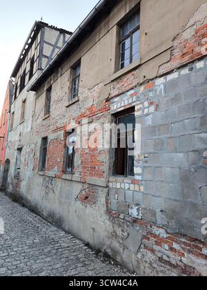 An old crumbling brick and stucco building facade on a cobblestone street Stock Photo