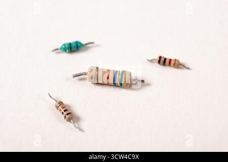 Different electrical resistors. Color-coded electrical resistors on yellow paper background texture, components, close-up Stock Photo
