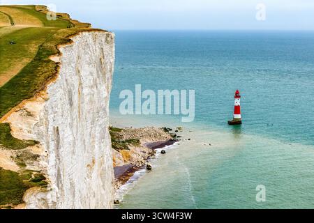 Famous red and white striped lighthouse at the foot of dramatic chalk cliffs on the coast. Stock Photo