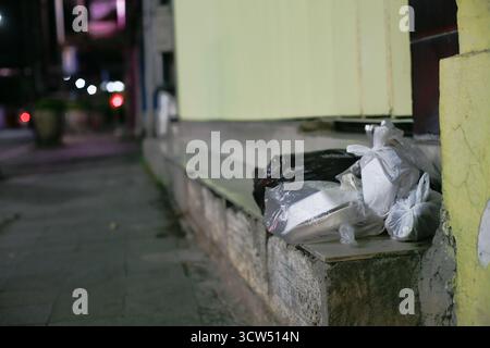 plastic takeaway packaging and foam boxes left on the side of the road at night Stock Photo