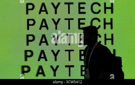 A man (silhouetted) walks past a LED screen displaying the word Pay Tech on the last day of the sixth Global Fintech Fest (GFF) in Mumbai. The three day event held from 7-9th October 2025, a global platform to encourage major stakeholders of Fintech firms, who gathered to share and exchange ideas, and innovation in banking, finance, artificial intelligence, digital payments, startups, and new technologies concluded on the last day with Indian Prime Minister Narendra Modi and United Kingdom Prime Minister, Keir Starmer addressing the delegates present at the event. (Photo by Ashish Vaishnav/S Stock Photo