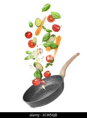 Frying pan and different flying vegetables on white background Stock Photo