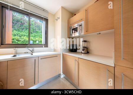 Modern Kitchenette with Light Wood Cabinets and White Countertops in mediterranean real estate Stock Photo
