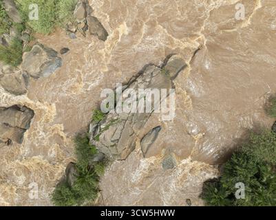 Aerial view of the turbulent, muddy river rushing around and over the rocks, a powerful display of nature's force, Webuye, Bungoma County, Kenya. Stock Photo