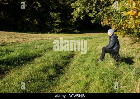 Man sitting on bench enjoy the autumn sun on his face in quiet moment alone, peaceful moment Stock Photo