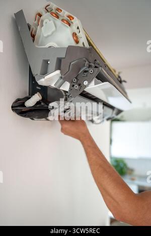 Damaged insulation on copper pipe of indoor air conditioner unit causing water leakage down wall Stock Photo